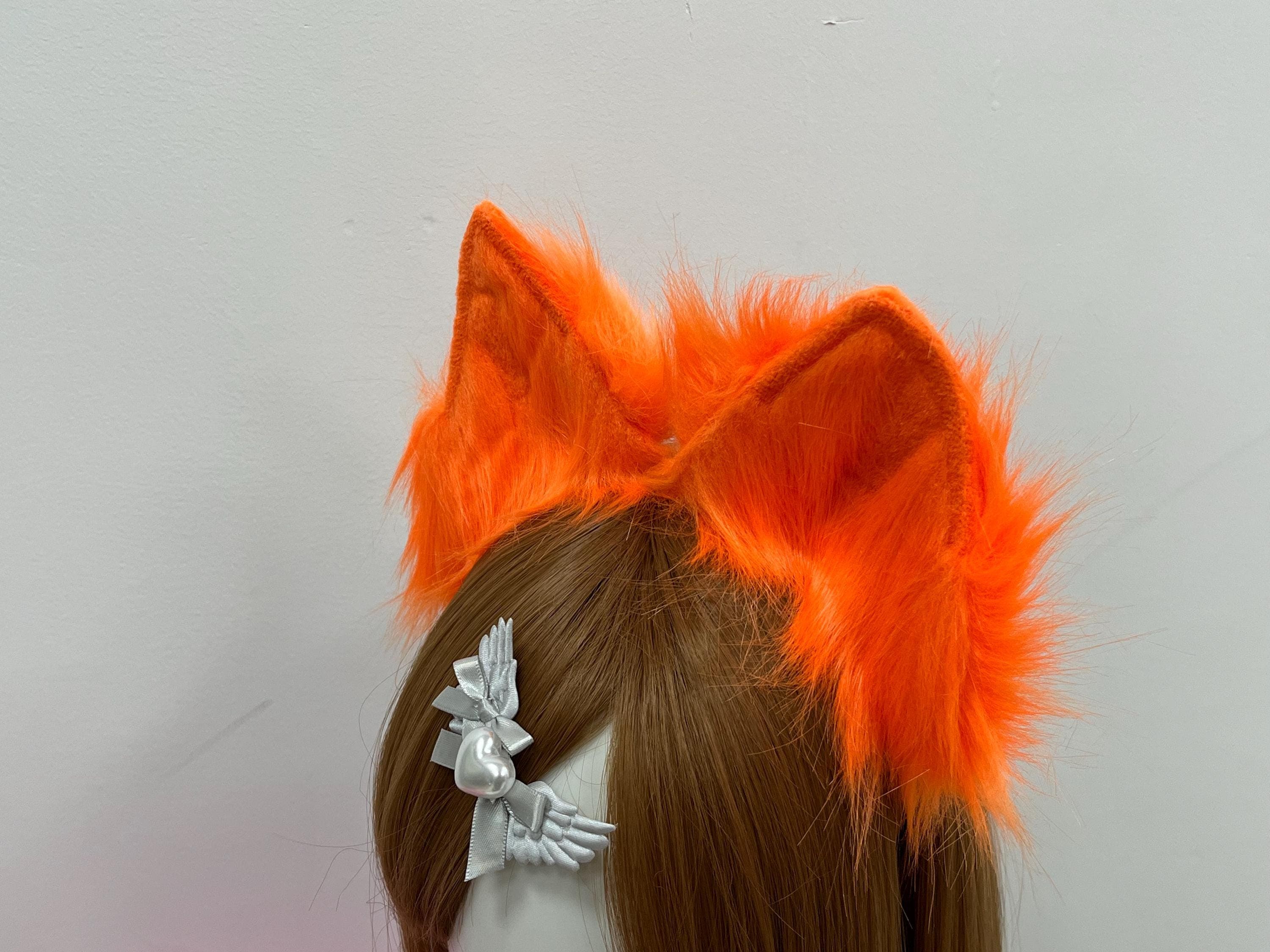 Angled rear view reveals layered fluff and the clean fox ear shape from behind, showing how dense orange faux fur sits naturally above the hairline without flattening. Inner velvet edging frames each peak in a darker tangerine outline. Perfect alt-mode finishing piece for fire foxes, mythic vixens, kitsune OCs, monster girls, and ren faire huntress builds where a pop of warm color pulls the whole costume kit together for con day or golden seasonal shoots.