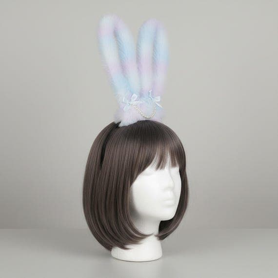 Yellow gradient pastel bunny ears headband on mannequin head with dark brown wig, plush faux fur rabbit ears with warm yellow to white ombre gradient, pearl bead and satin bow detail at base, black headband, studio lighting on neutral background