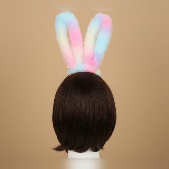 Rear view of pastel gradient bunny ears headband on mannequin head with brown wig showing back of plush faux fur rabbit ears, soft ombre gradient coloring visible from behind with smooth fur texture, pearl bead and satin bow at base, 24cm tall oversized ears for cosplay costumes anime conventions Halloween parties Easter celebrations and festival dress-up, kawaii pastel rainbow bunny ear headpiece back angle for styling reference, fluffy rabbit ear headband for photo shoots and themed party look