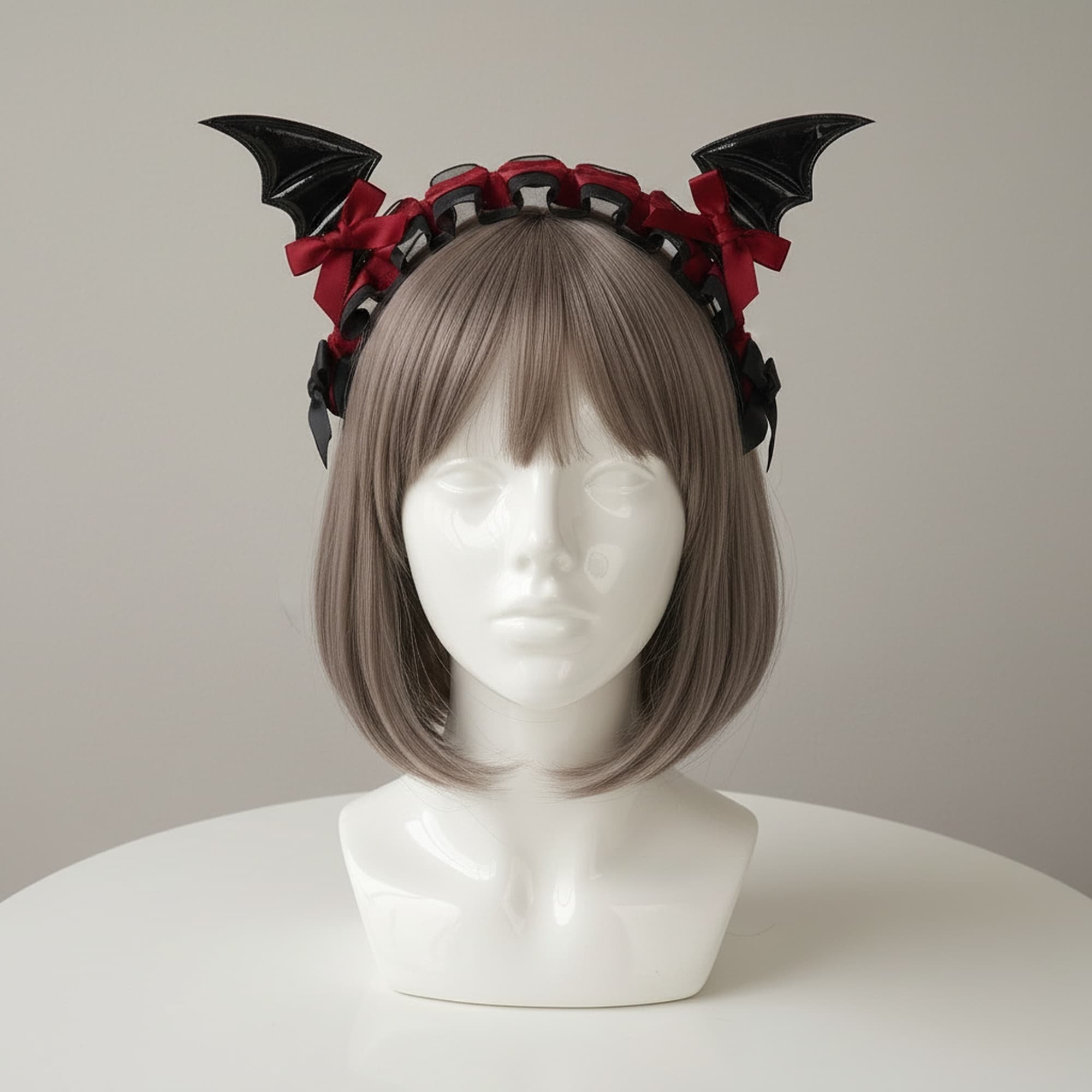 Black and red bat wing lace headband with glossy PU leather wings and crimson satin ribbon bows on organza ruffle band displayed on mannequin with grey brown bob wig. Gothic cosplay costume ears accessory for halloween vampire demon dark fashion anime con festival rave. Lightweight gothic lolita style headband with intricate lace ruffle detail and bat wing silhouette. Perfect for dark fairy succubus vampire cosplay photography content creation