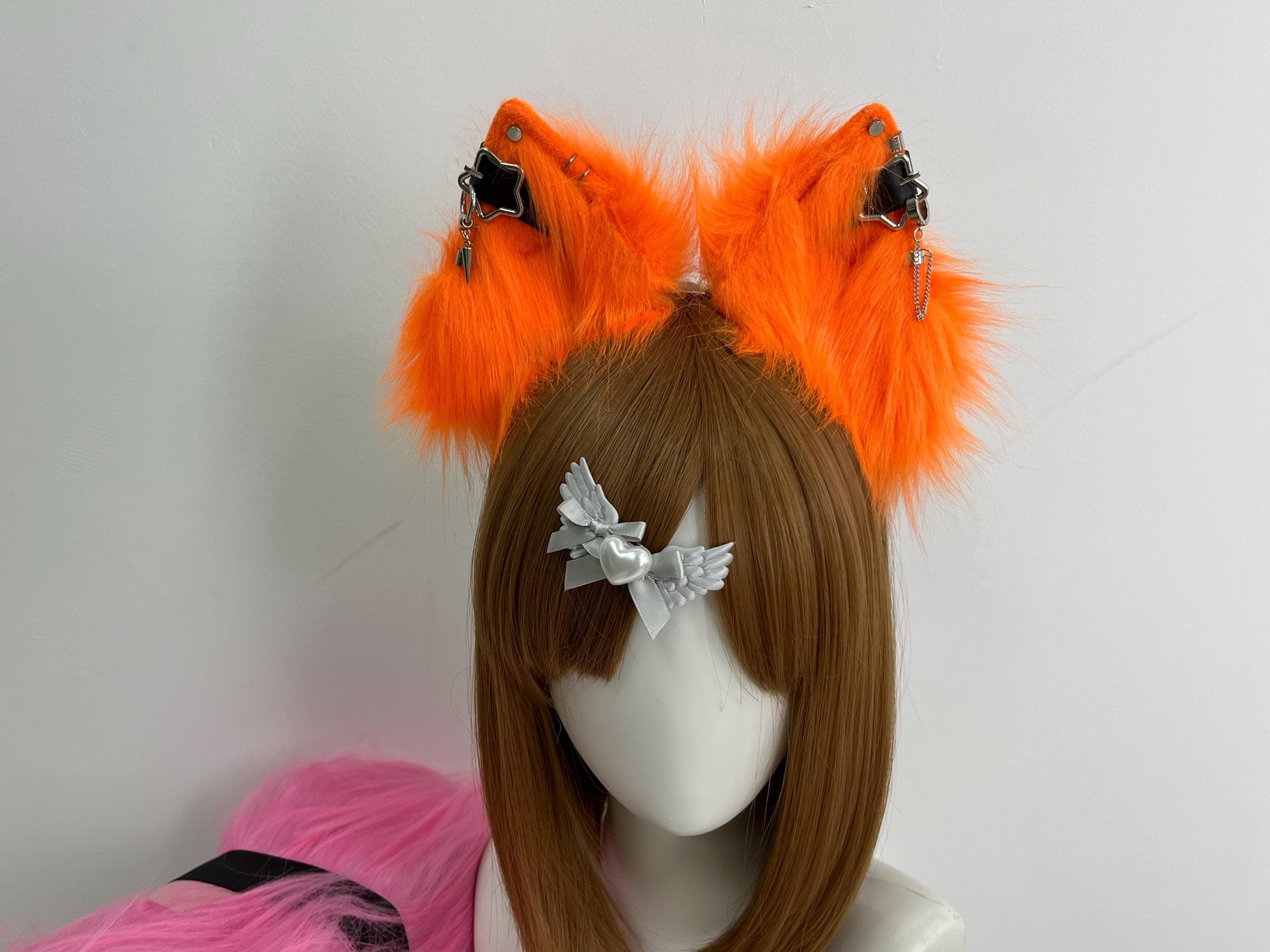 Handmade neon orange faux fur wolf ears headband shown front view, featuring tall pointed realistic wolf ear shape with vibrant tangerine pile and signature silver star chain piercings with tiny spike charm drops. Perfect kemonomimi accessory for anime cosplay looks, Halloween costume parties, furry fursona builds, kitsune roleplay, and LARP fire elemental characters. Lightweight comfy headband stays put all day and makes an instant statement at any con with a bright alert wolf silhouette.